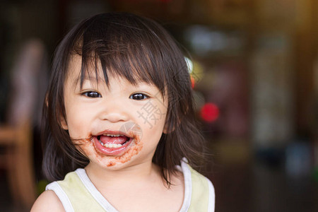 岁婴儿的肖像图快乐的亚洲小女孩喜欢带着甜美的微笑吃香蕉食物和健图片