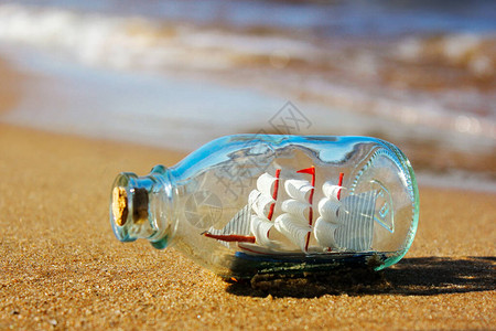 瓶子里的船躺在水边的沙滩上来自大海的纪念品美好回忆和海图片