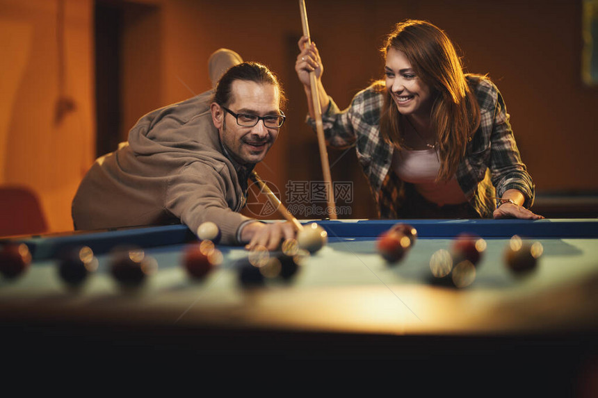 快乐笑脸的年轻夫妇下班后在酒吧里打球图片