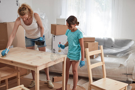母亲和女儿在新公寓中绘画和装配家具搬图片