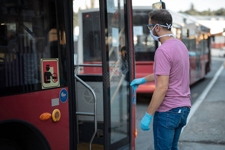 戴医疗防护面具和手套的人在公共交通站上进入公共汽车中时图片