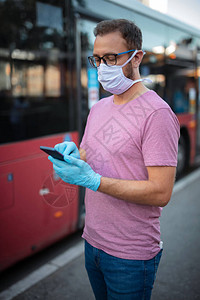 戴医疗防护面具和手套的人在公共汽车站上等待公共交通图片