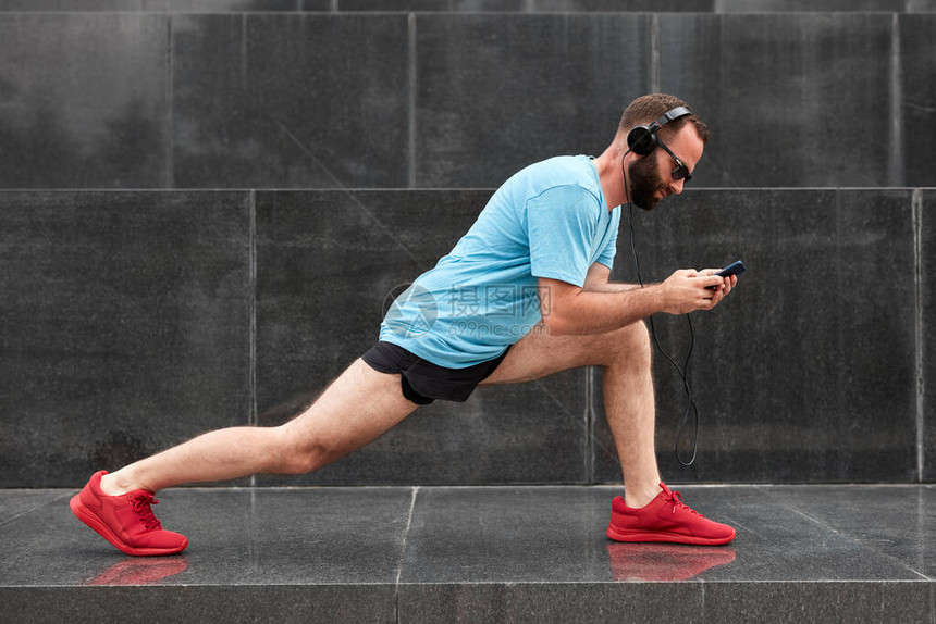 现代运动男子在城市环境慢跑锻炼后暂停和伸图片