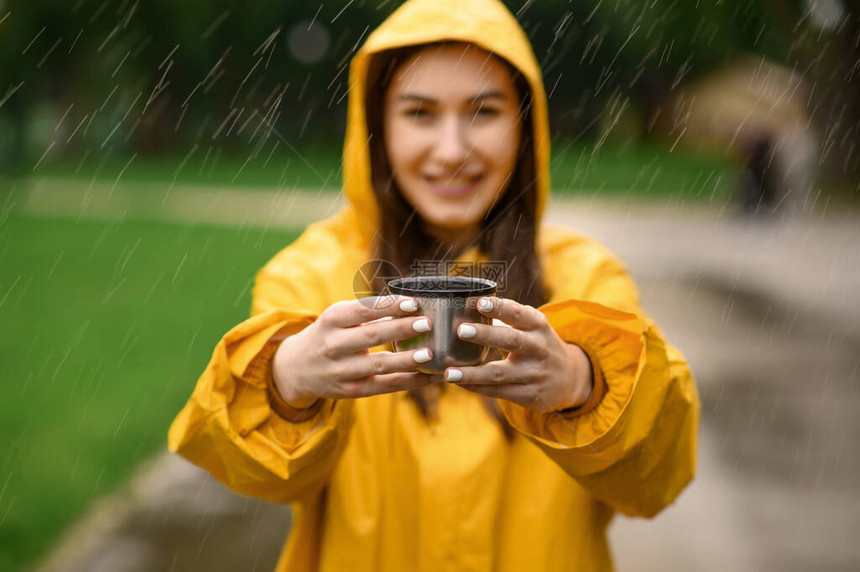 穿雨衣的女人拿着一杯热茶图片