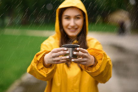 穿雨衣的女人拿着一杯热茶图片