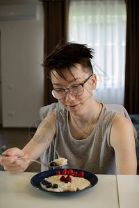 一个十几岁的孩子吃燕麦粥和浆果图片