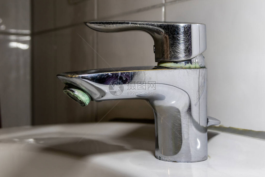 用于淋浴或水龙头水槽的卫生间中带有不锈钢镀铬设备的旧化石浴室配件和化石卫浴由于镀铬扳手上滴水而图片
