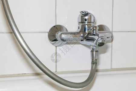 用于淋浴或水龙头水槽的卫生间中带有不锈钢镀铬设备的旧化石浴室配件和化石卫浴由于镀铬扳手上滴水而背景图片