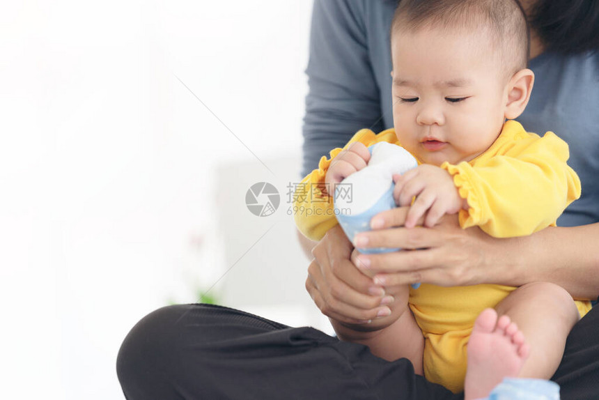 慈爱的妈在家里的沙发上给婴儿穿鞋图片