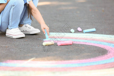 小女孩用粉笔在沥青上画图片