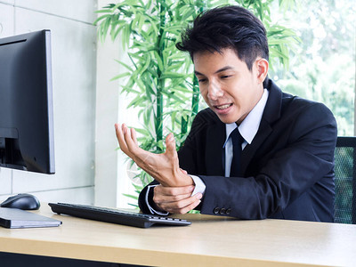 年轻亚洲商人在办公室使用笔记本电脑时图片
