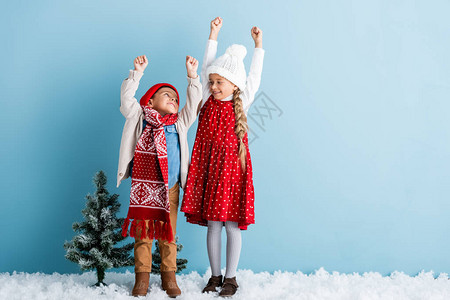 孩子们穿着冬装双手举过头顶蓝色地站图片