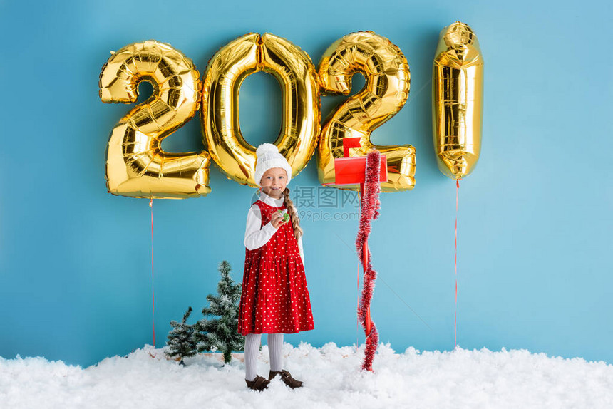 身穿冬装的小孩在邮箱和有数字的气球旁边拿着礼物图片