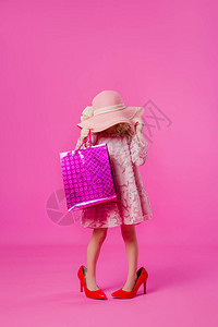 女孩穿着她母亲的大鞋衣服帽子和购物袋图片