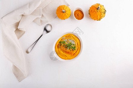 香辣南瓜汤配南瓜籽和欧芹白桌上有秋南瓜汤的碗顶视图片