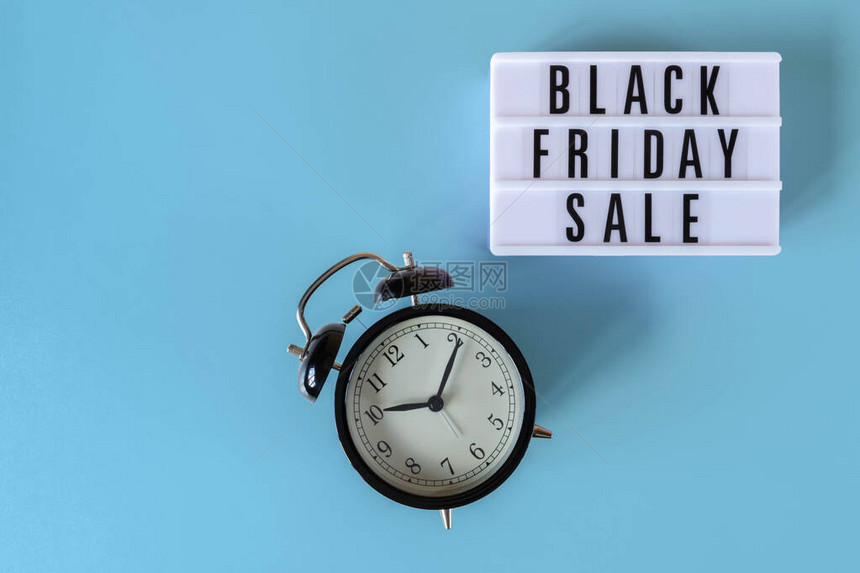 白色灯箱上的黑色星期五销售文本和蓝色背景上的闹钟促销广告黑色星期五标图片