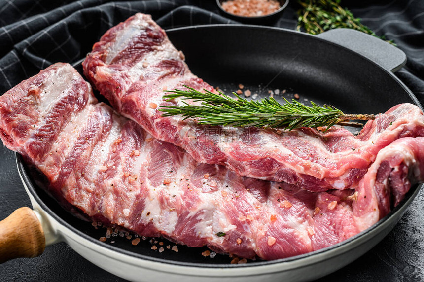 原猪肉排骨配香料和草药在锅里黑色背图片