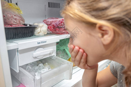 一个奇怪的女孩看着冰柜冷冻器图片
