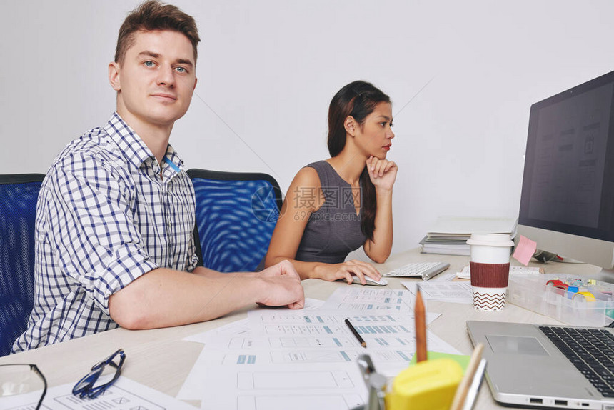 UX和UI设计师在新移动应用程序接口工作时坐在彼此旁边的UX图片