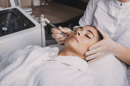新氧换肤躺在一家温泉沙龙的黑发女士用新设备治愈后背景