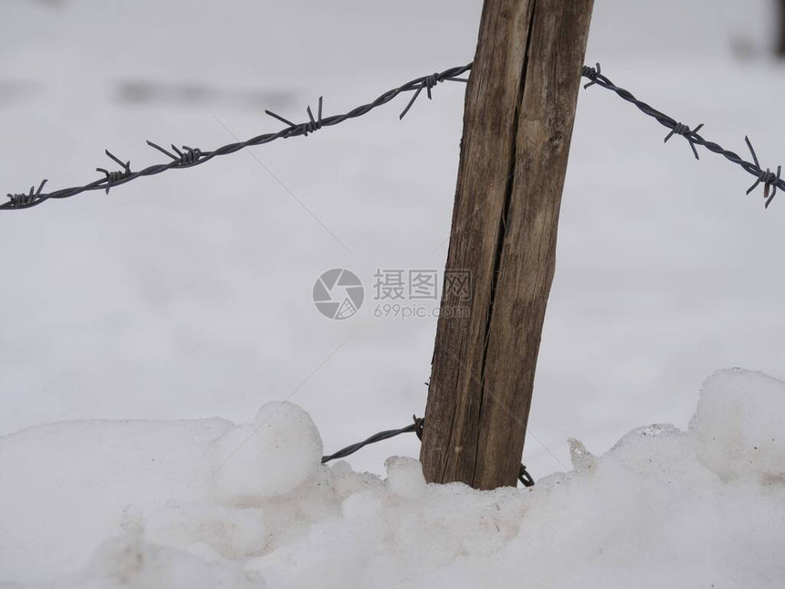 地上有铁丝网和雪的木柱图片