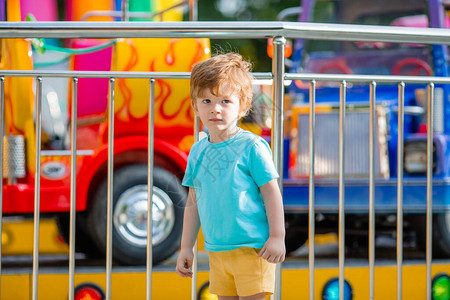 穿着蓝色T恤的快乐小男孩在夏日游乐园散步图片