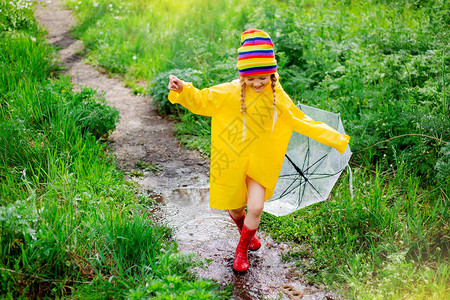 穿着黄色雨衣和透明伞的快乐女孩图片