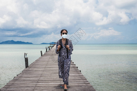 戴保护面罩的旅游妇女走在带海洋图片