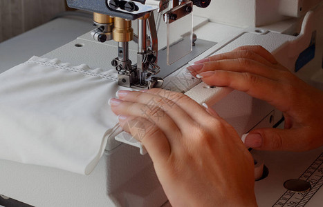 女人在工业缝合制纫机上缝衣手握近身图片