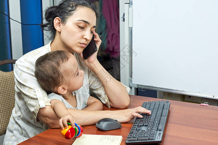 妈在打电话年轻的母亲在家工作时照顾她的孩子母亲和儿子在家由于冠状病图片