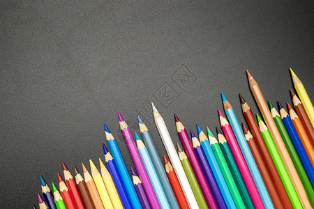 教育背景学校文具以及教室黑纸板上的彩色铅笔粉笔和刷子图片