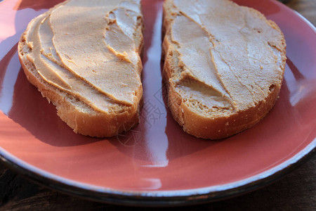 木制背景花生酱吐司盘子上花生糊的面包切片儿童健康零食顶视图片