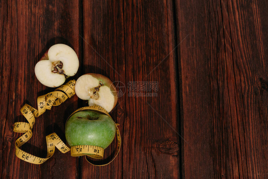 一个完整的青苹果和一个切成片的红苹果放在木制厨房桌子上图片