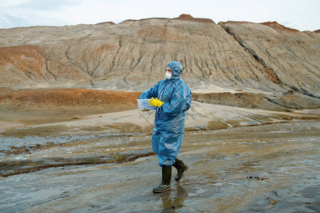 当代保护覆盖物呼吸器橡胶手套和靴子中的女科学家图片