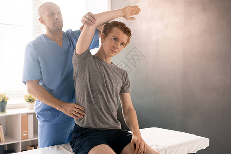 年轻病人在康复诊所侧盆锻炼期间坐在医疗沙发上时图片