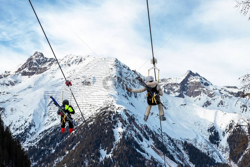 一对带滑雪设备的观光游客享受乘坐极短悬浮的铁丝网图片