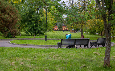 一位年轻运动妈和婴儿车坐在公园的木凳上图片