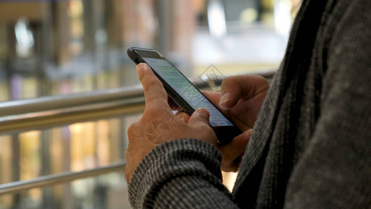 男人手在购物中心背景上发短信的特写男双手使用他的智能手机在社图片