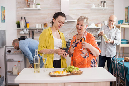 母亲和女儿在厨房里使用智能手机图片