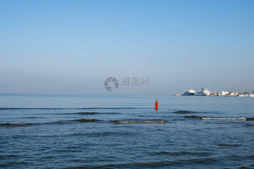 站在海边的渔夫在日出时钓到一条鱼旋转钓鱼爱好图片