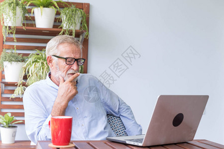 退休老人在家中用笔记本电脑工作在家图片