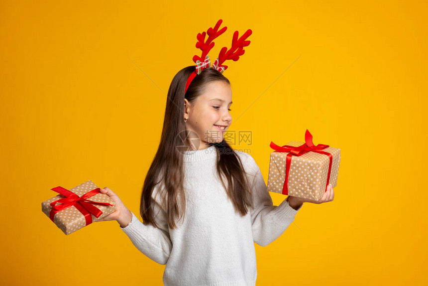 带着毛衣角微笑的小女孩小女儿拿着节日礼物图片