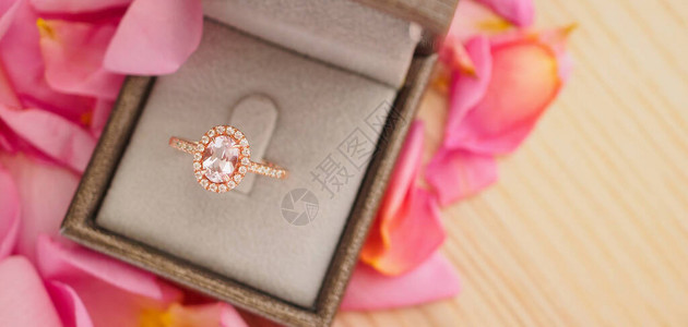 美丽的粉红玫瑰花瓣背景的珠宝盒里有优雅的婚礼钻图片