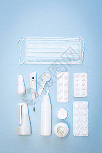 蓝色背景的医疗面具白色温度计药片喷鼻喷剂的图片