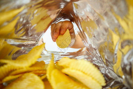 手拿薯片放在零食箔袋里图片