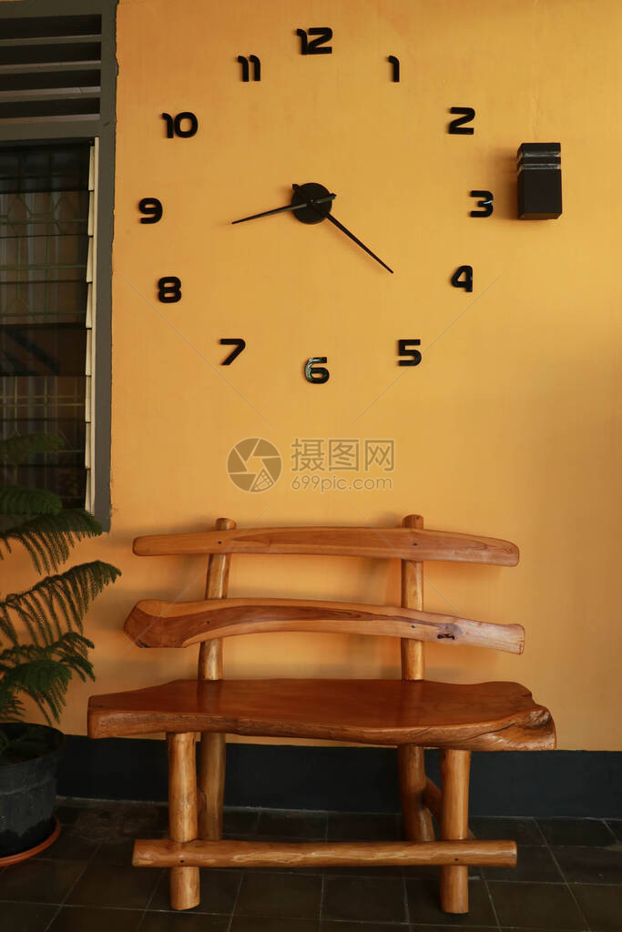 黄色墙附近的木板凳壁钟下图片