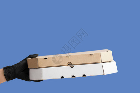 手戴防护手套和彩色背景的披萨盒图片