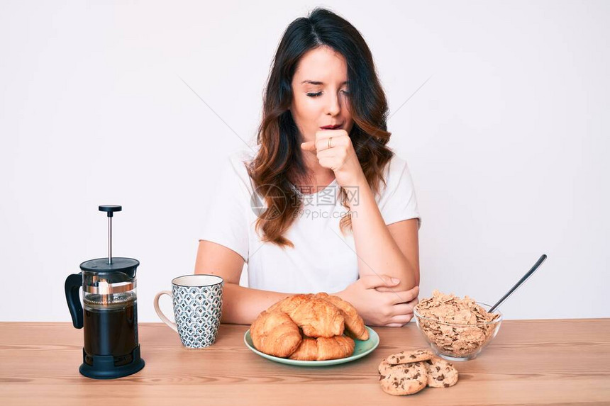 早上坐在桌边吃早餐的年轻美丽的棕发女人感到不舒服图片