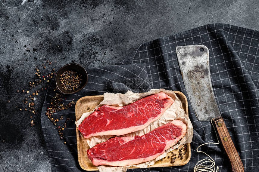 Rawsirloin牛排在木质餐具上配着肉刀大牛肉黑色背景顶层视图片