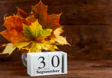 9月30日在木制日历上和一束枫叶色的秋天秋季月份的日期图片